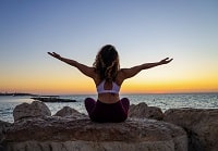Picture of woman outside at the beach in a yoga seated position