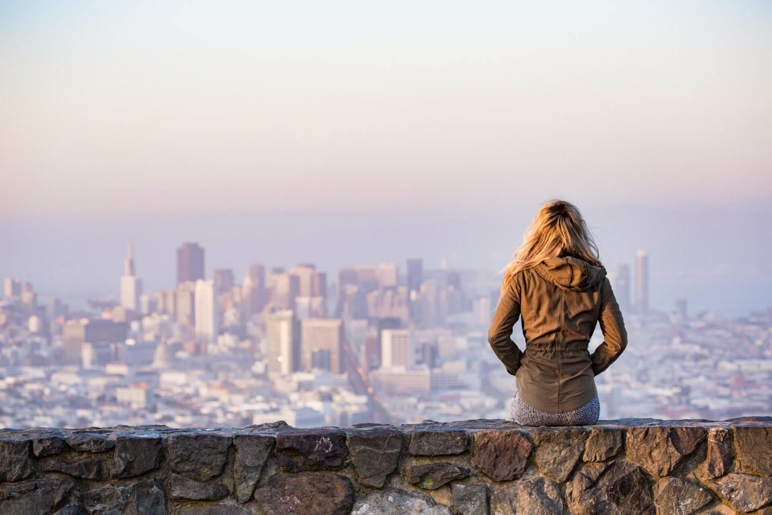 A woman on a rock overlooking a big city